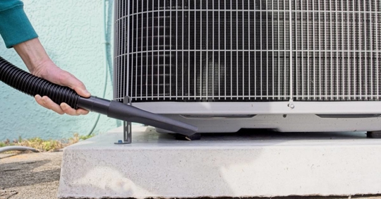 Homeowner vacuums around heat pump to ensure peak efficiency